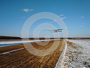 Takeoff of an old biplane plane from a winter airfield from a runway with grass with a blue sky background