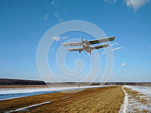 Takeoff of an old biplane plane from a winter airfield from a runway with grass with a blue sky background