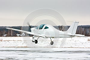 Takeoff the small sport airplane at winter airfield