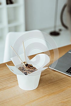 takeout box with noodles and chopsticks on workplace