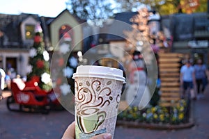 Takeout paper coffee cup against blurred Christmas decorations