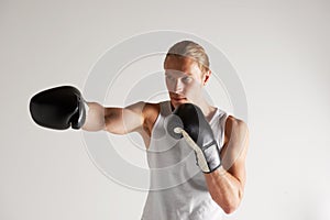 He takes his boxing career very seriously. A handsome young male boxer wearing a vest and throwing a punch.
