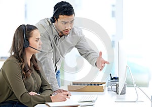 It takes a team to execute a sales dream. a businessman and businesswoman using a headset and computer while working in