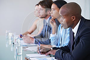 Taking in all the facts. businesspeople taking notes while listening to a presentation at a conference.