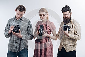 Taking another shot. Paparazzi or photojournalists with vintage old cameras. Retro style woman and men hold analog photo