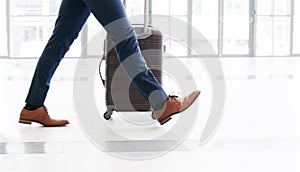 Taking big steps towards success. Cropped shot of an unrecognizable businessman walking and pulling a suitcase while in