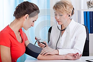 Taking blood pressure of female patient