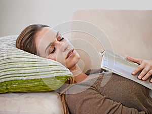 Taking this book into dreamworld. an attractive woman napping on the sofa with a book.