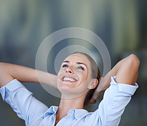 Taking a break from it all. A young businesswoman looking relaxed with her hands behind her head.