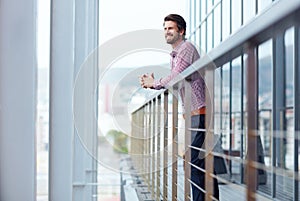 Taking a break on the balcony. a happy young businessman standing on the balcony of an office building.