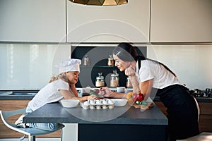 Taking a break. Mother with her daughter are preparing food on the kitchen