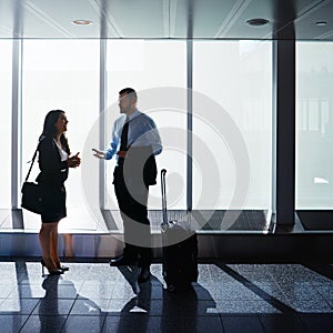 Taking business in departures. two businesspeople talking together in an airport.