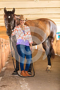 Cowgirl standing next to brown horse friend