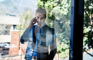 Taking care of business. Shot of a young businessman talking on the phone outside an office.