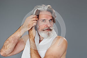 Taking care of face and skin clearness. Stylish modern senior man with gray hair and beard is indoors