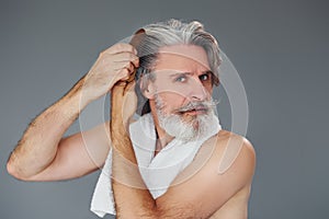 Taking care of face and skin clearness. Stylish modern senior man with gray hair and beard is indoors