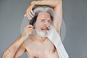 Taking care of haircut. Stylish modern senior man with gray hair and beard is indoors