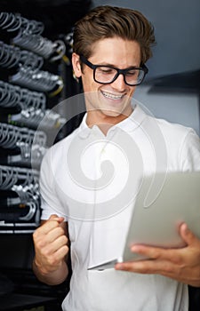 Taking care of your network needs. A technician in a server room looking at a laptop.