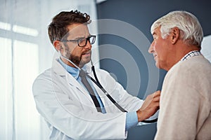 Taking a careful listen to his heart. a doctor examining a senior patient with a stethoscope in a clinic.