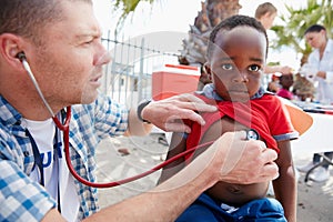 Taking a closer listen to his heart. a volunteer doctor giving checkups to underprivileged kids. photo