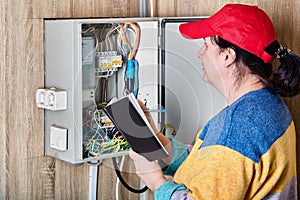 Taking electric meter readings by electrician with notebook.