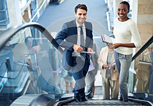 Taking the express route to success. Portrait of two businesspeople standing on an escaltor.