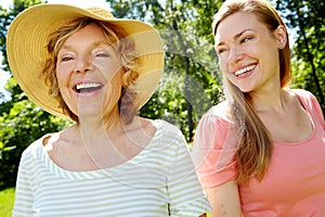 Taking a fun stroll in the park. A senior woman enjoying a relaxing stroll in the summer sun with her daughter.