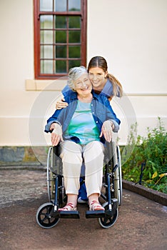 Taking her for a walk though the gardens. a resident and a nurse outside in the retirement home garden.