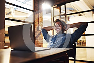 Taking the laid-back approach to business. a handsome young male designer looking relaxed while working late in his