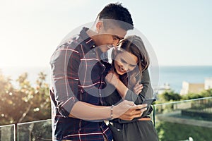 Taking a look at some priceless moments we captured together. Shot of an affectionate young couple using a cellphone