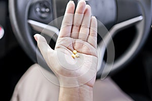 taking medication before driving concept with the woman hand holding pills in a car photo