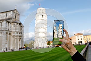 Taking a mobile photo of leaning Pisa Tower during vacation in Italy