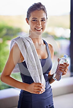 Taking a moment to quench her thirst. Portrait of an attractive young woman relaxing after a workout.