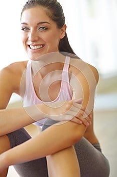 Taking a moment to relax. A happy young woman sitting in an exercise class and smiling.