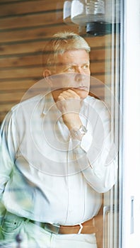 Taking a moment to think it over...a contemplative senior man looking out from his bedroom window.