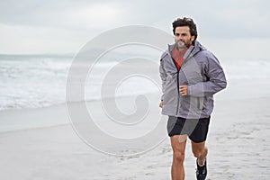 Taking a morning run on the beach. a handsome young man running on the beach.