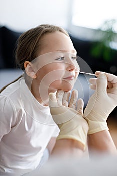 Taking nasal mucus test sample from elementary age girl`s nose performing respiratory virus testing procedure