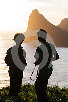 Taking in natures magnificence. Rearview shot of two men enjoying an ocean view from a hilltop.