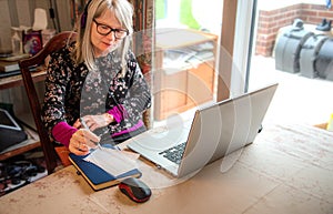 Digital nomad woman watching webinar on her laptop,wearing headphones photo