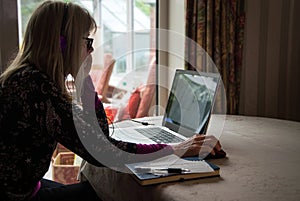 Self employed woman watching webinar on her laptop,wearing headphones photo