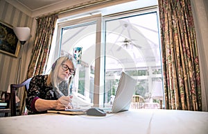 Woman watching webinar on her laptop,wearing headphones photo