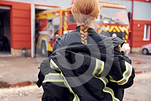 Taking off the protective clothes. Woman firefighter in uniform is at work in department