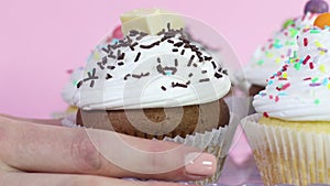 Taking one delicious cup cake with white cream and colorful crumbs