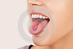 Taking painkiller pill on tongue.