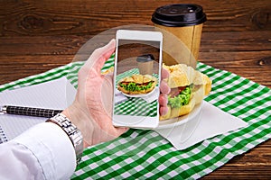 Taking photo of meat sandwich on mobile phone