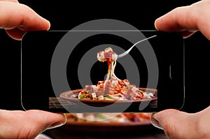 Taking photo of pasta by smartphone. Closeup view of process. File contains clipping paths for smartphone and hands and picture on