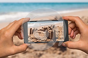 Taking photo of sand castle with mobile phone