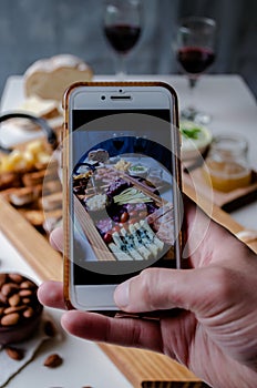 Taking photograph of food served on the table with your smartphone. Charcuterie. Picada Argentina