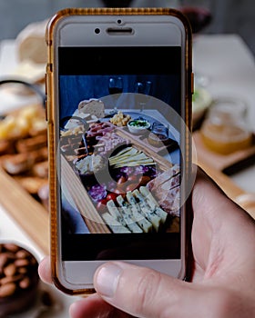 Taking photograph of food served on the table with your smartphone. Charcuterie. Picada Argentina