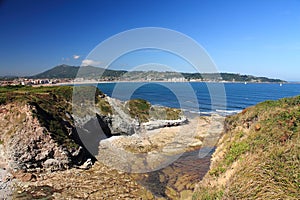 taking photos on coastal pathway with panoramic view of beautiful atlantic coast with beach, ocean and mountain jaizkibel in blue